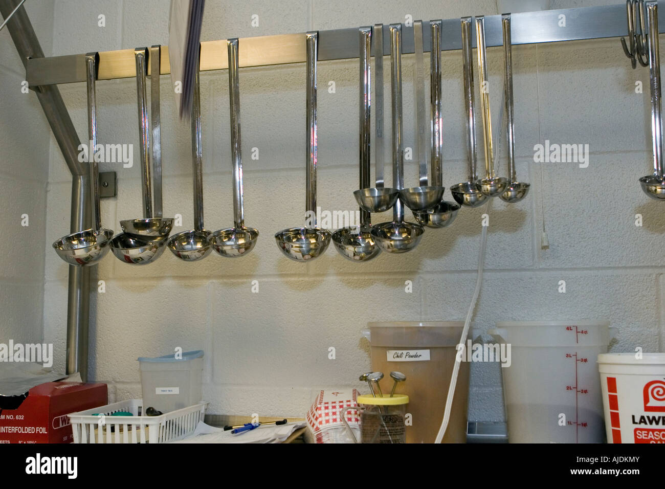 Various size ladles hanging from rack in school kitchen Stock Photo