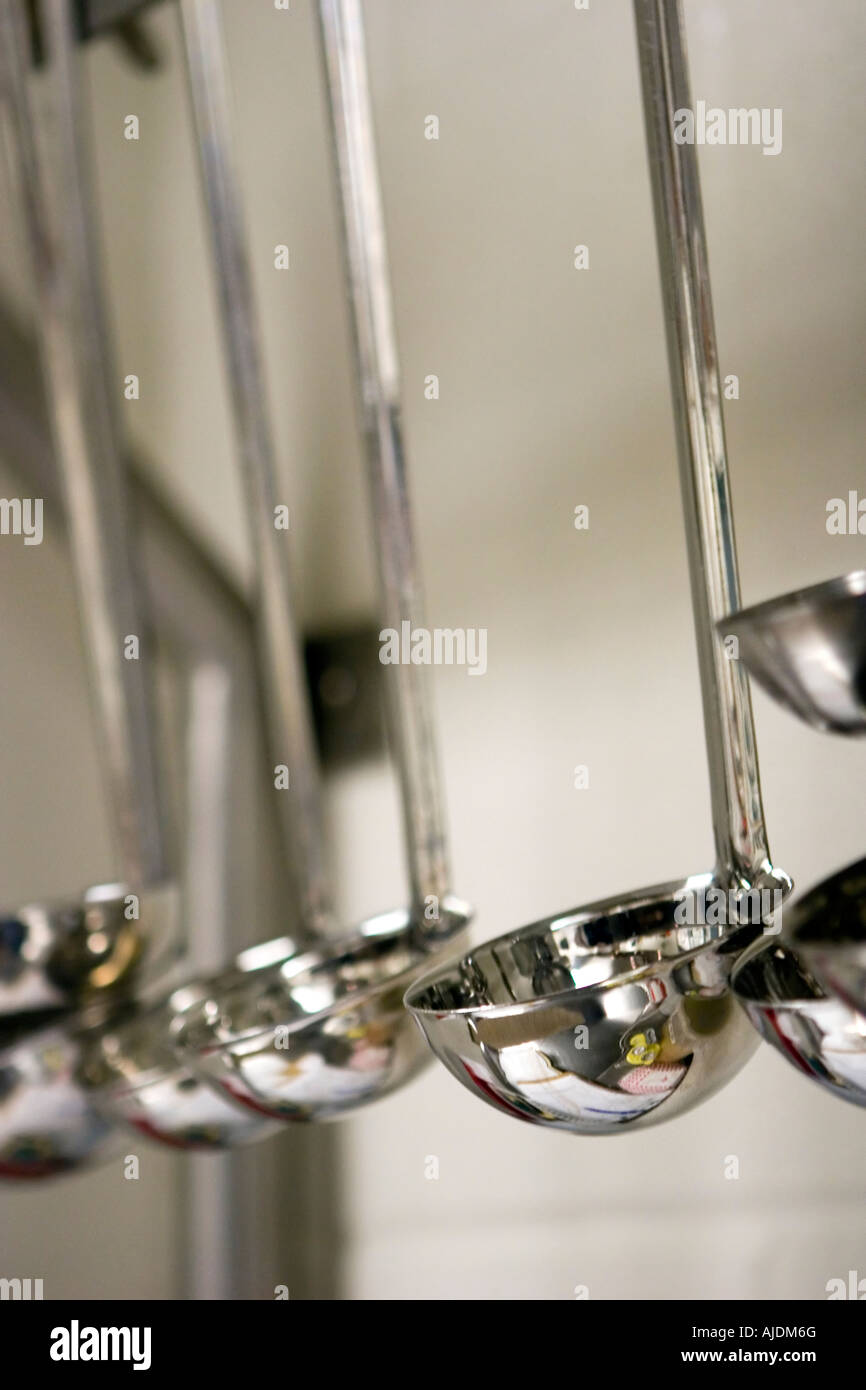 Various size ladles hanging from rack in school kitchen Stock Photo