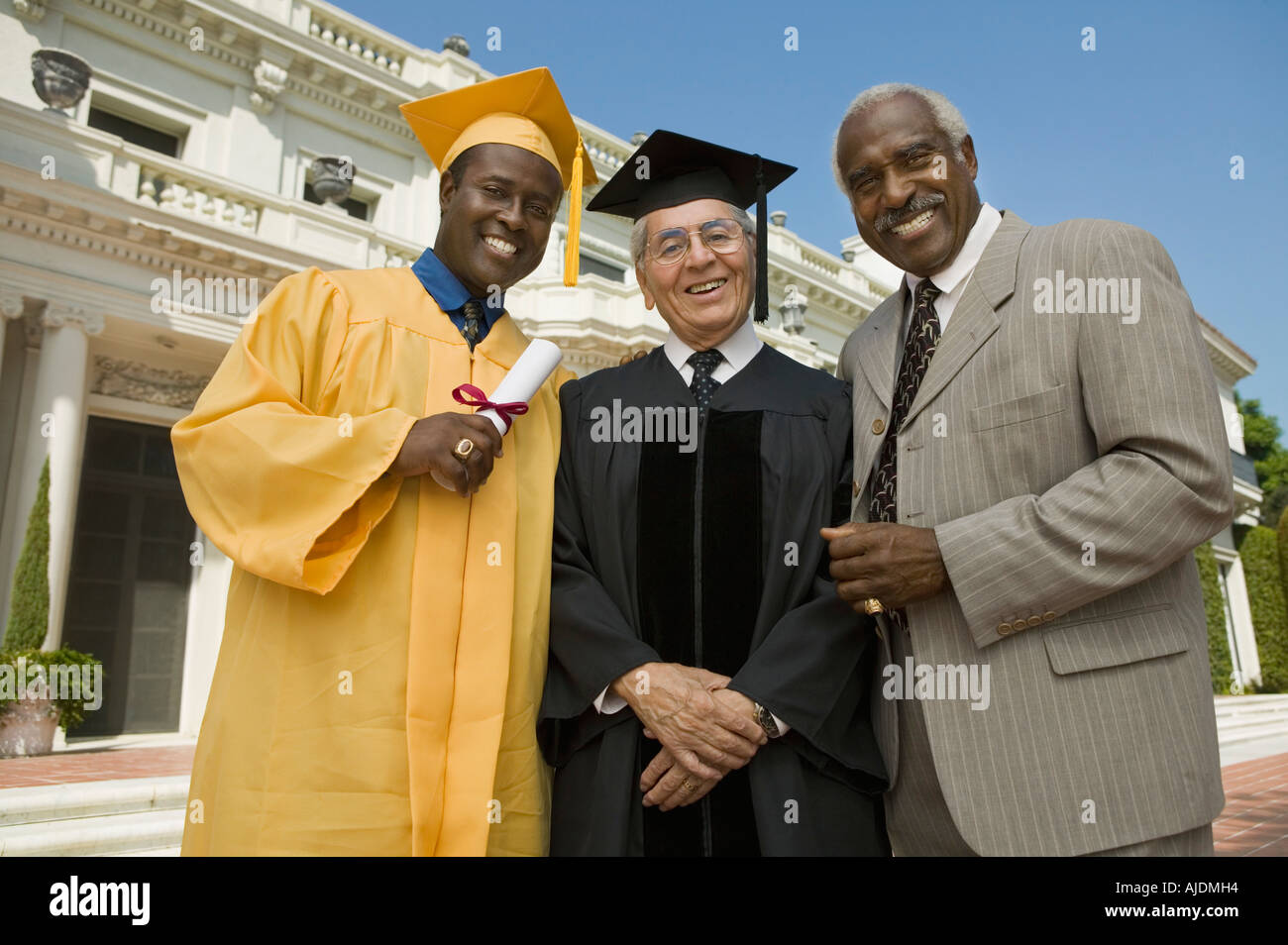 Graduate with dean and father outside university, low angle view, portrait Stock Photo