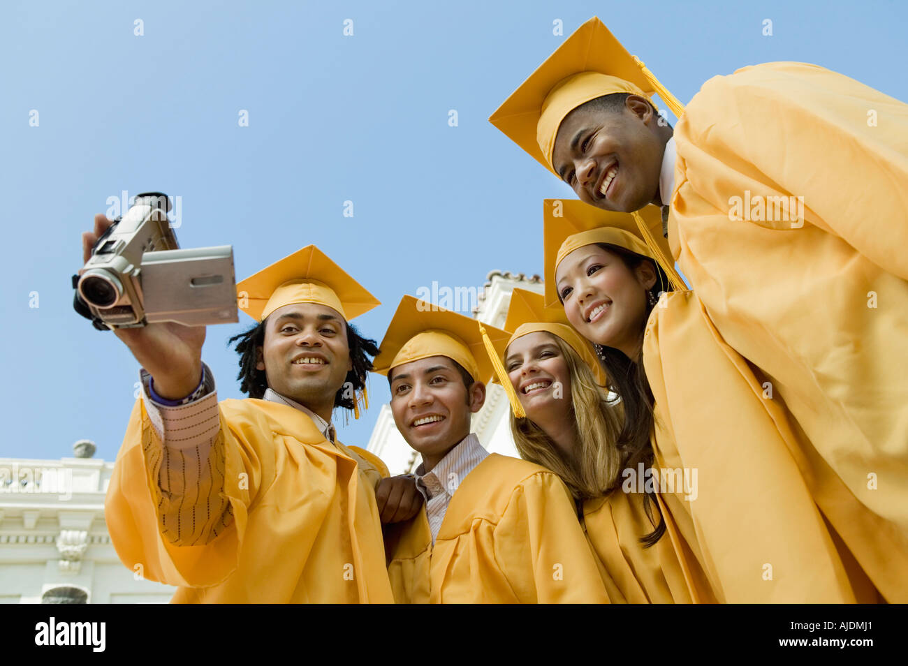 Group of graduates using video camera outside, low angle view Stock Photo