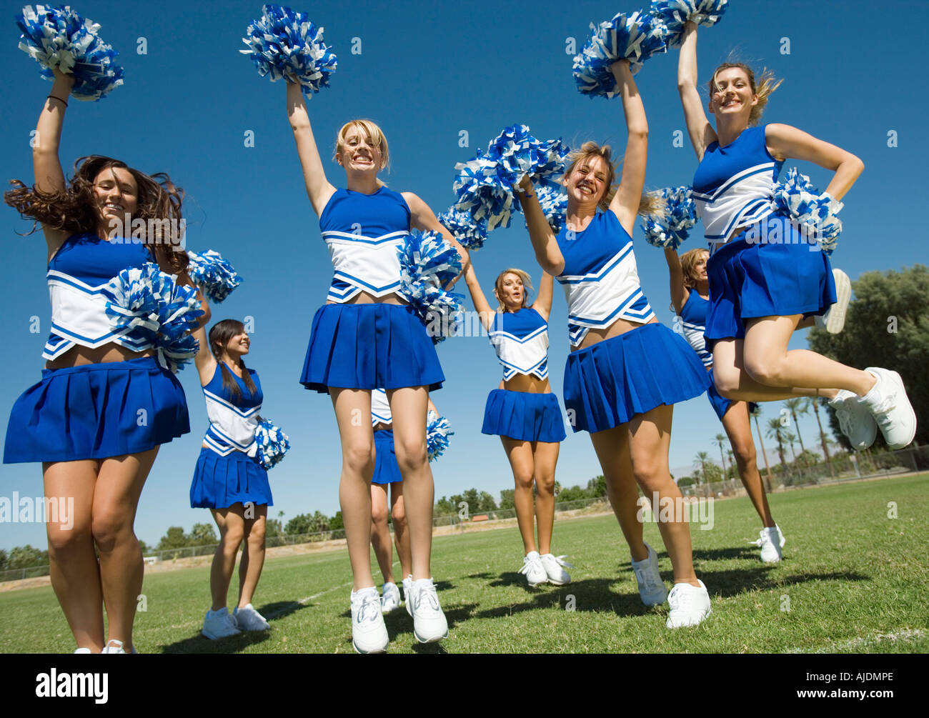 Group of Cheerleaders rising pom-poms, jumping football field Stock - Alamy