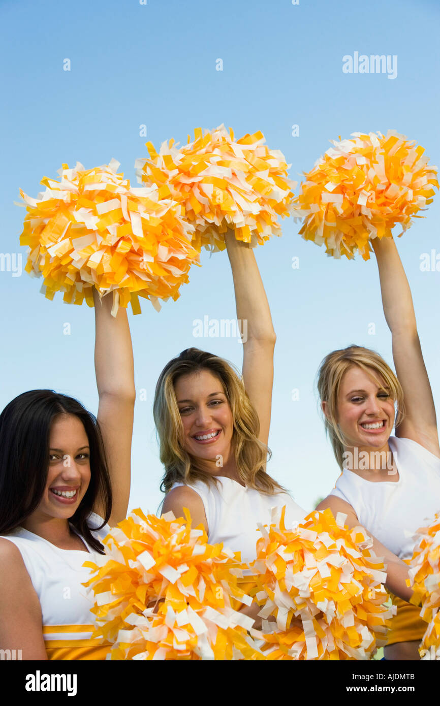 Three Cheerleaders rising pom-poms, (portrait) Stock Photo