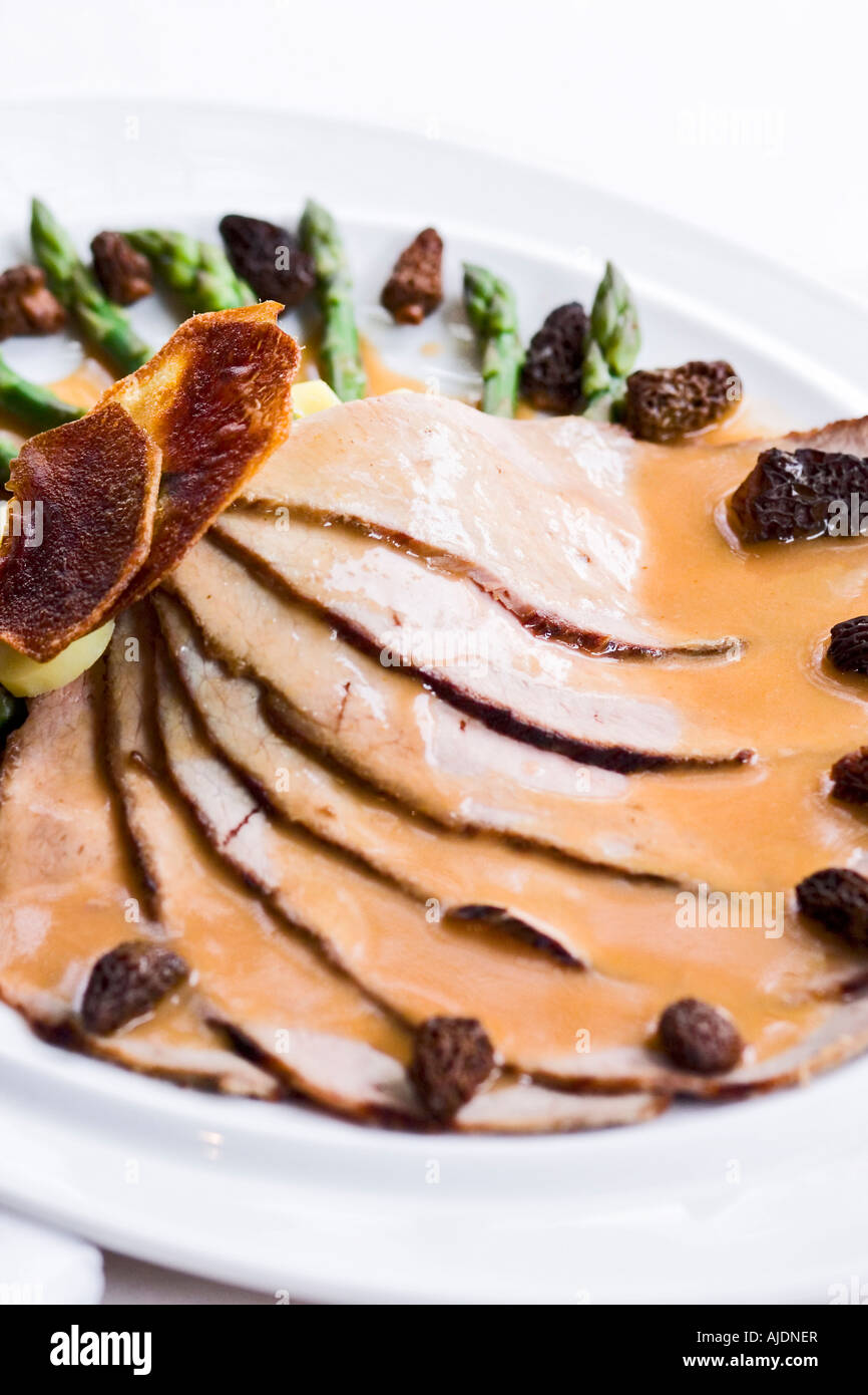 Sliced meat with gravy and asparagus on plate Stock Photo