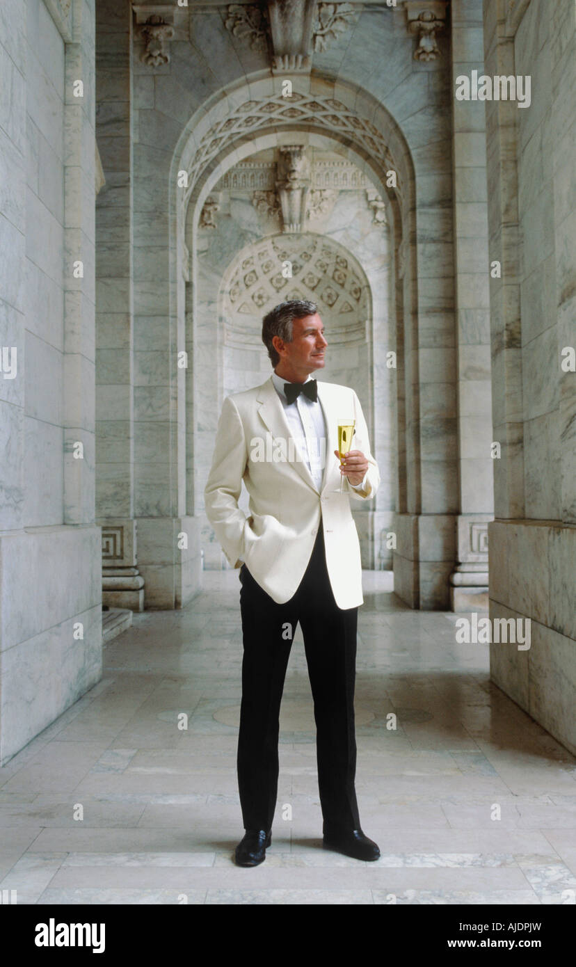 Wealthy aristocratic millionaire in white tuxedo holding a champagne glass  under a marble arch Stock Photo - Alamy
