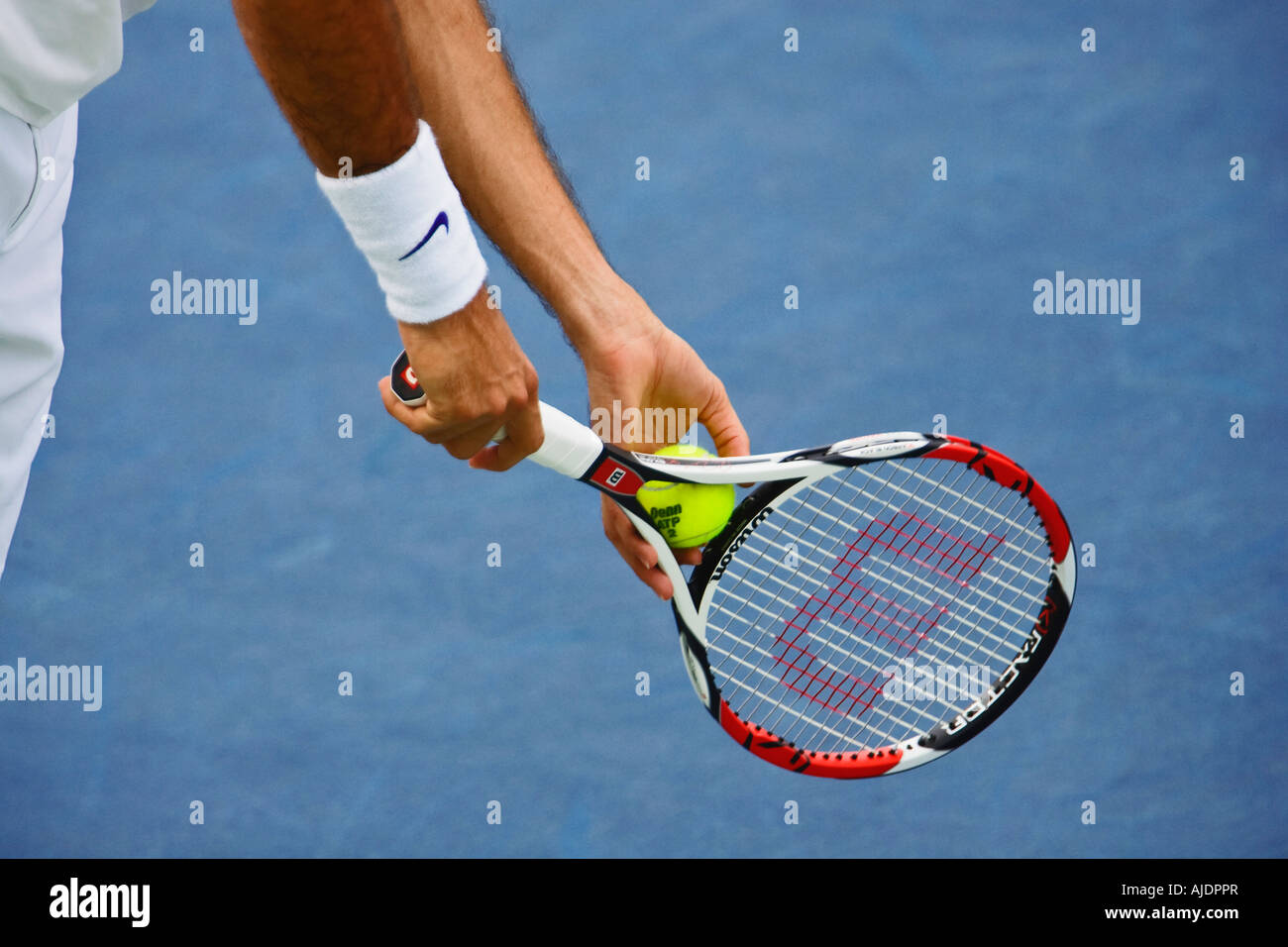 Professional tennis player prepares to serve ball to opponent. Stock Photo