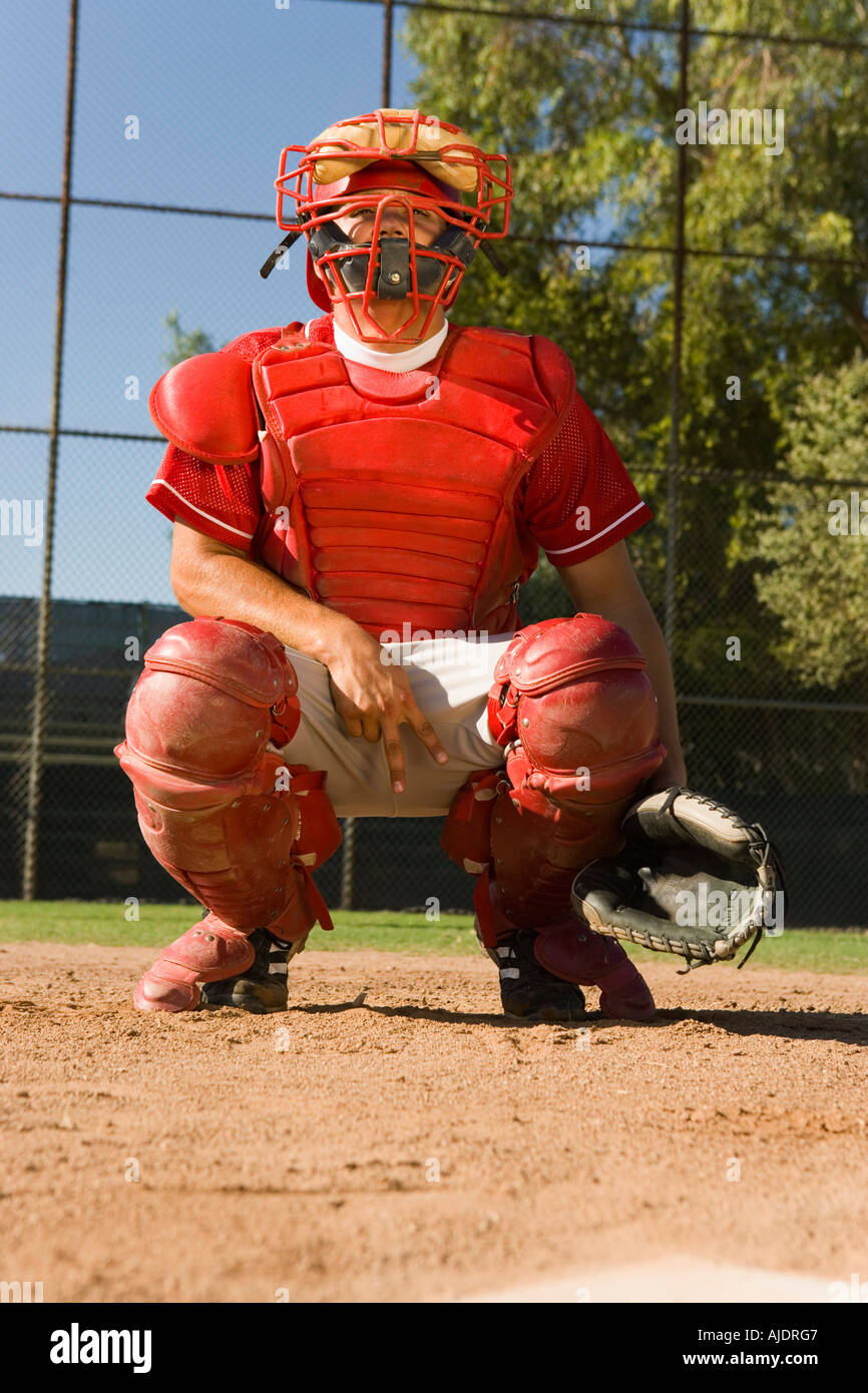 Baseball catcher crouching on baseball field, giving hand signals Stock