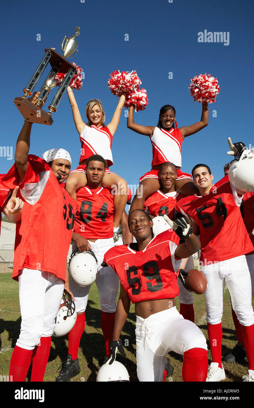 Football players and cheerleaders holding up trophy Stock Photo