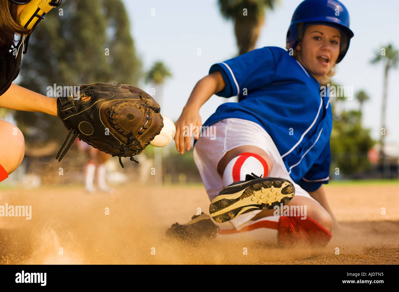 Softball player sliding into home plate Stock Photo