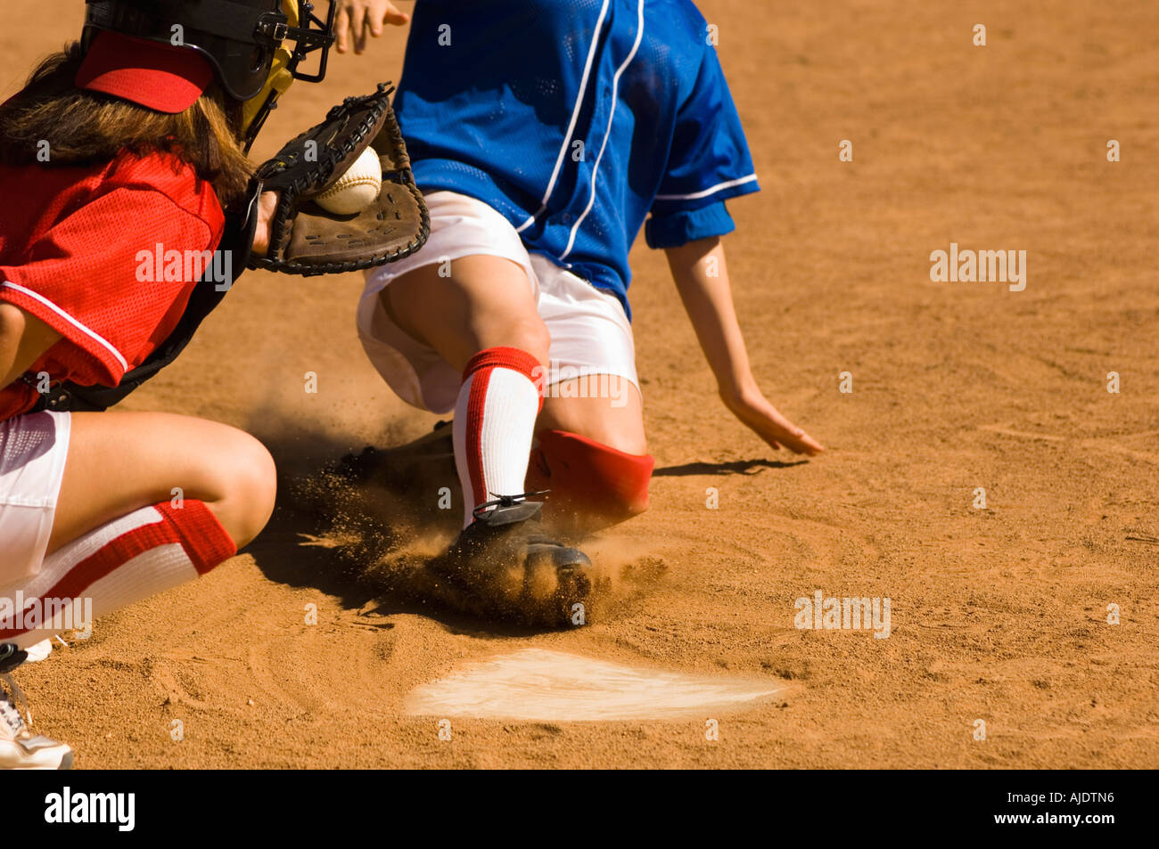 Softball player sliding into home plate, low section Stock Photo