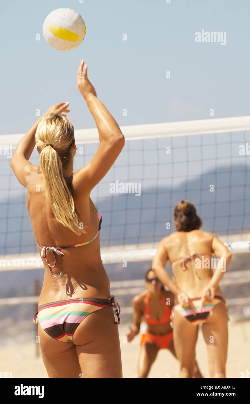 Female beach volleyball player serving volleyball, back view Stock