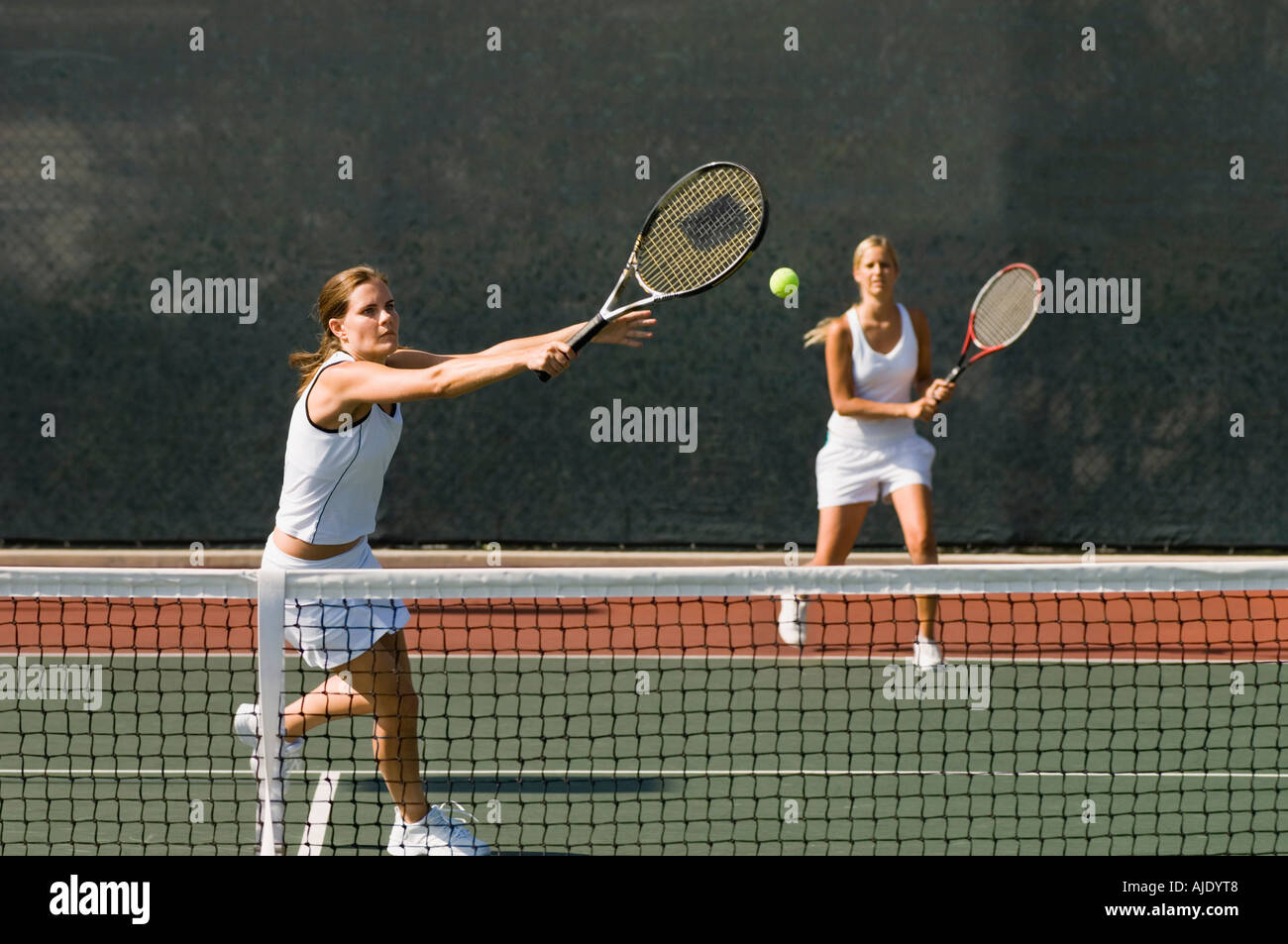 Doubles Player stretching, Hitting tennis ball with Backhand near net Stock Photo