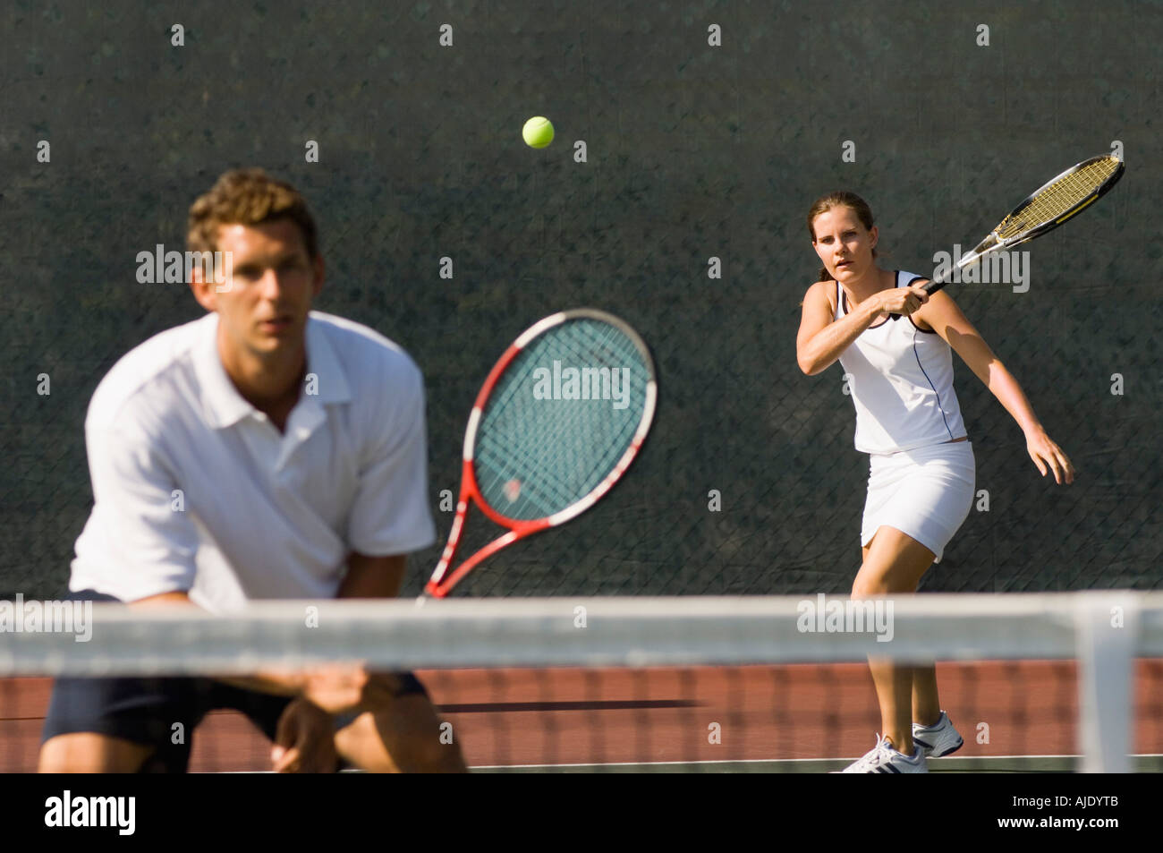 Mixed Doubles player hitting tennis ball, partner standing near net Stock  Photo - Alamy