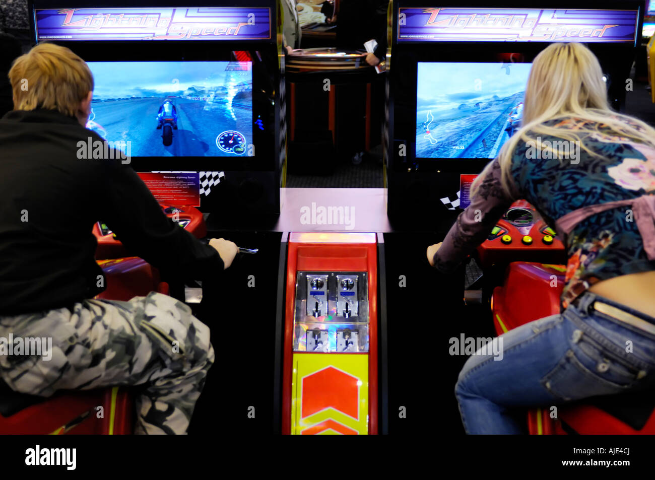 Young people riding motorcycle racing video game Lightning Speed on slot machines Stock Photo