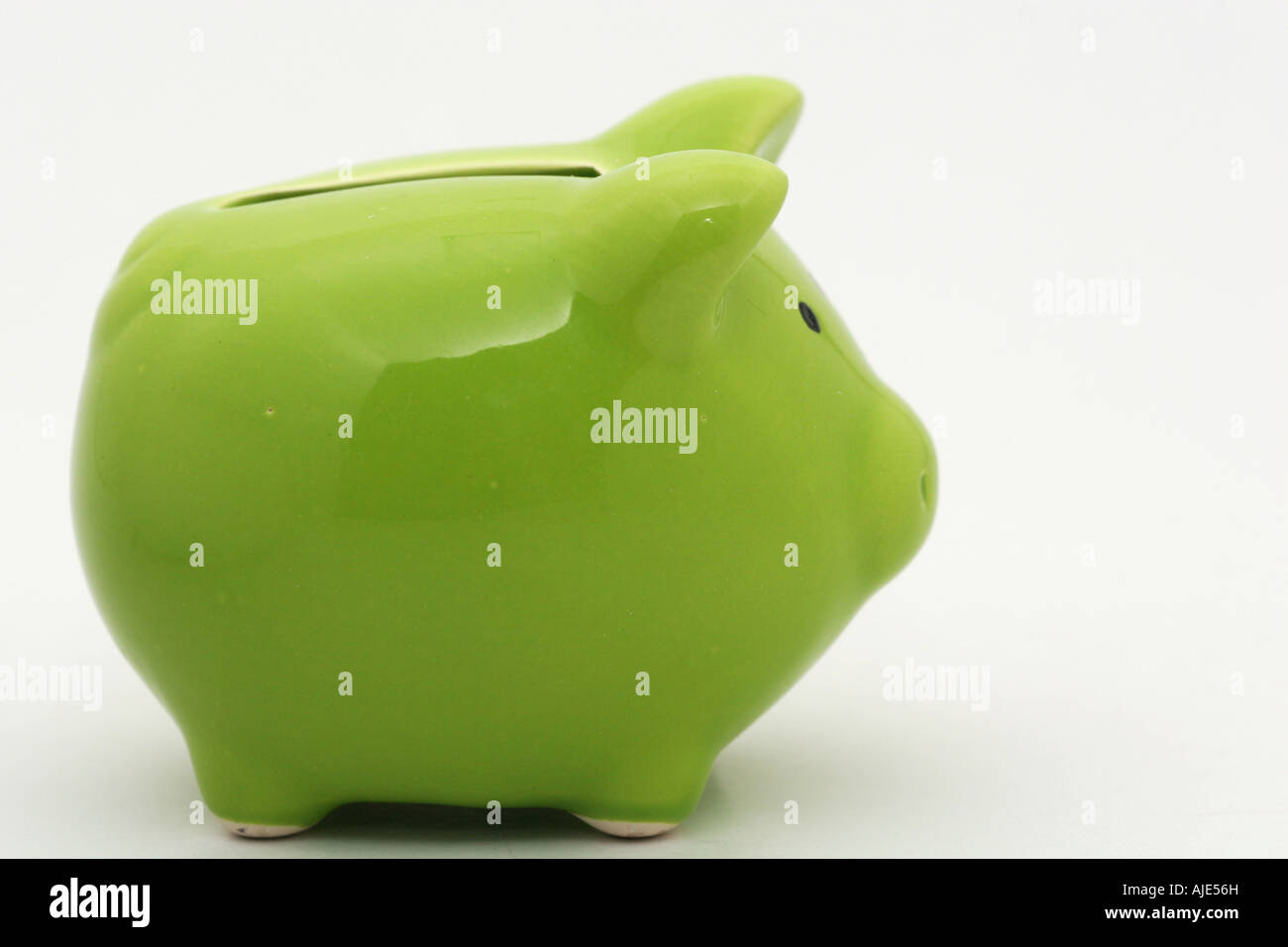 A green piggy bank isolated on white background shot from the side ...