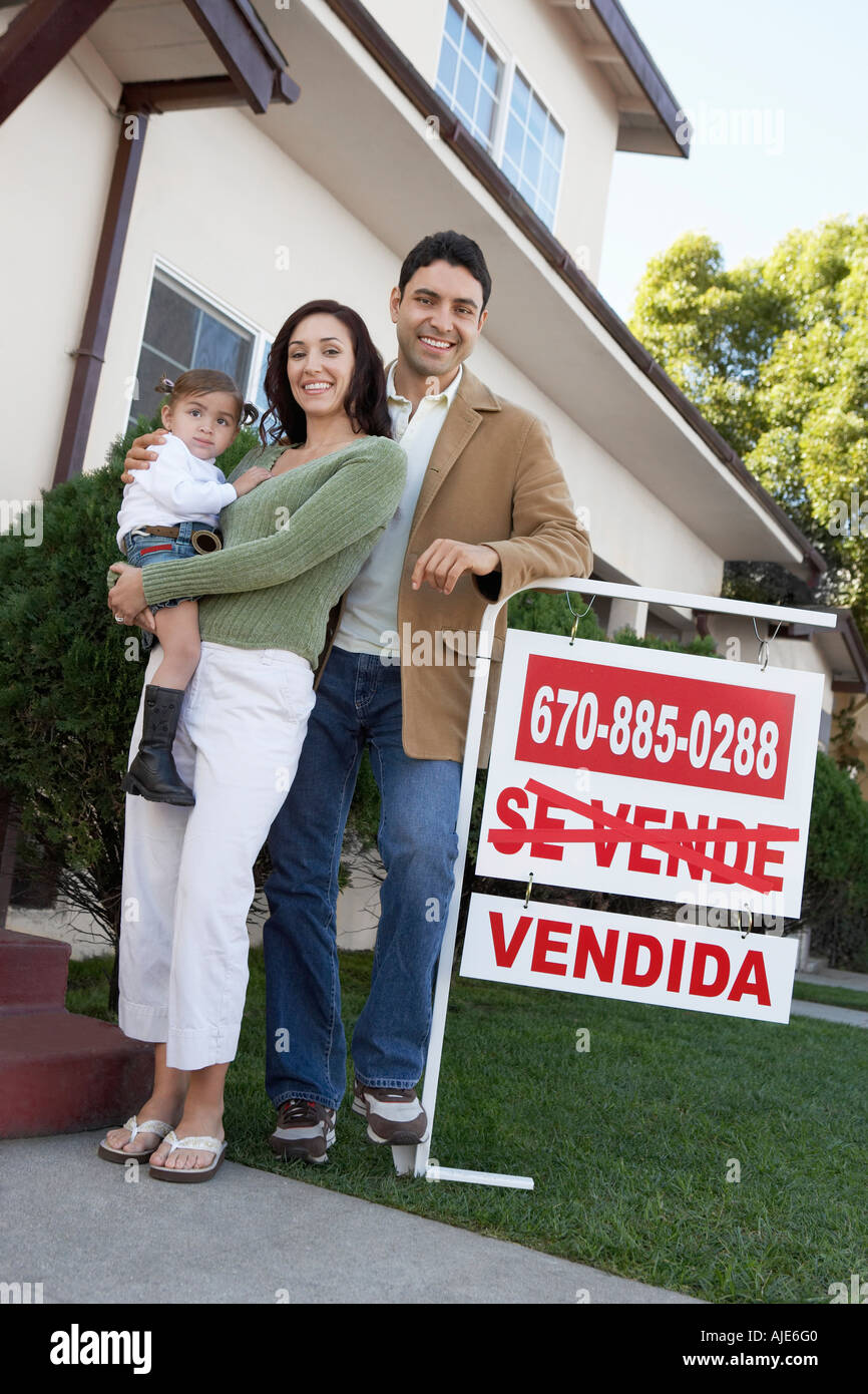 Family standing in front of house with For Sale sign, portrait Stock ...