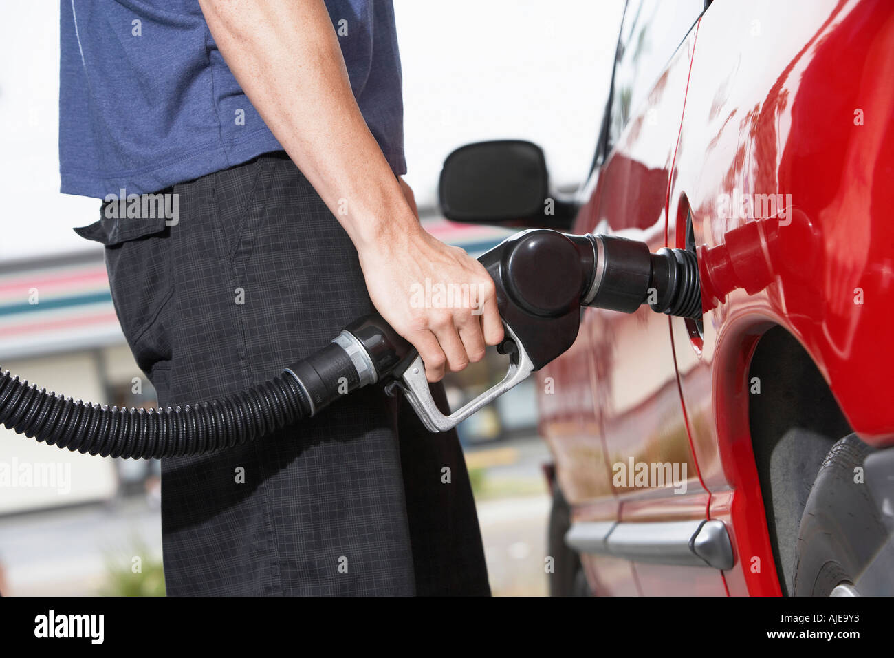 Young man filling car with gas at gas station, mid section Stock Photo