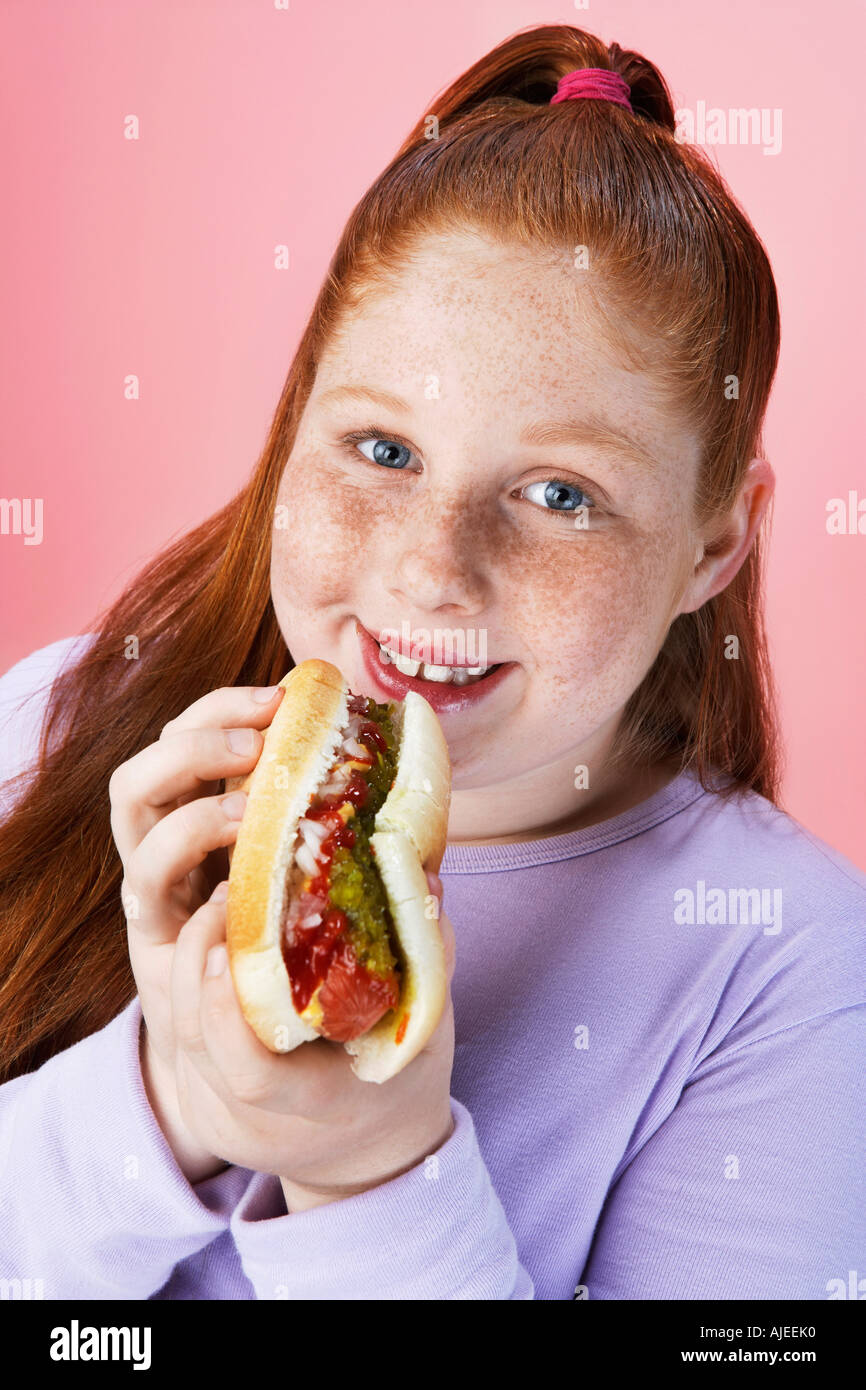Overweight girl (13-15) Eating hot dog, portrait, close-up Stock Photo