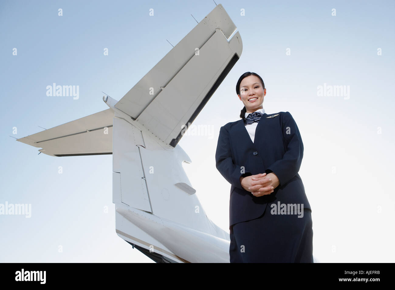 Stewardess in uniform, standing below wing of private jet, low angle view Stock Photo