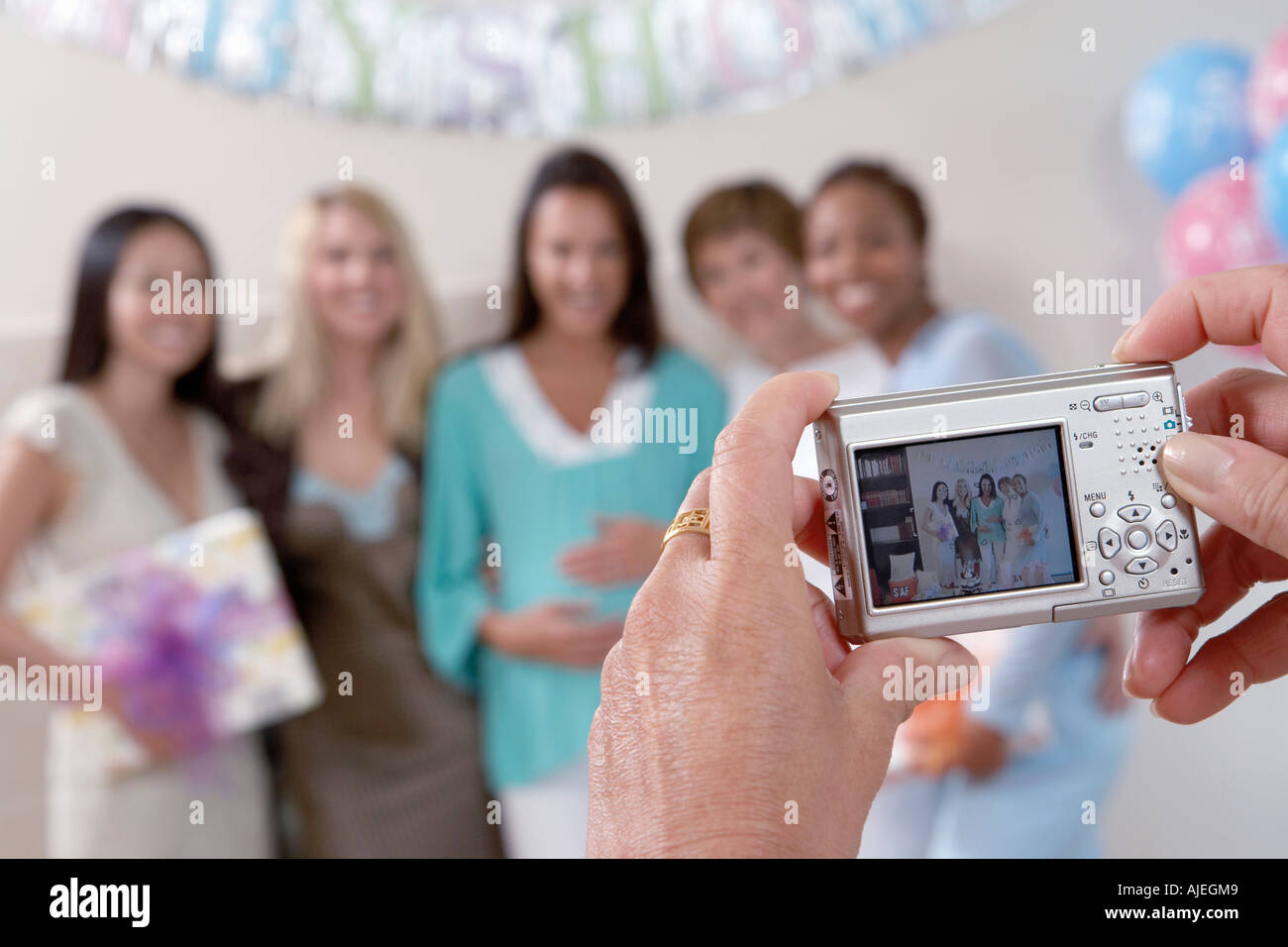 Woman taking photo of friends at baby shower, focus on camera Stock Photo