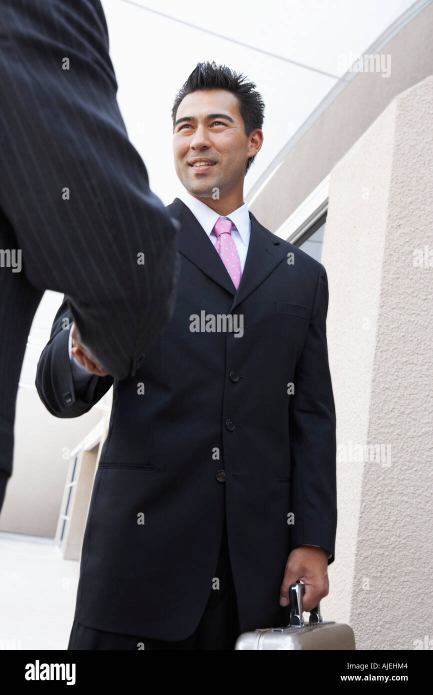Two Businessmen Shaking Hands outside office, low angle view Stock Photo