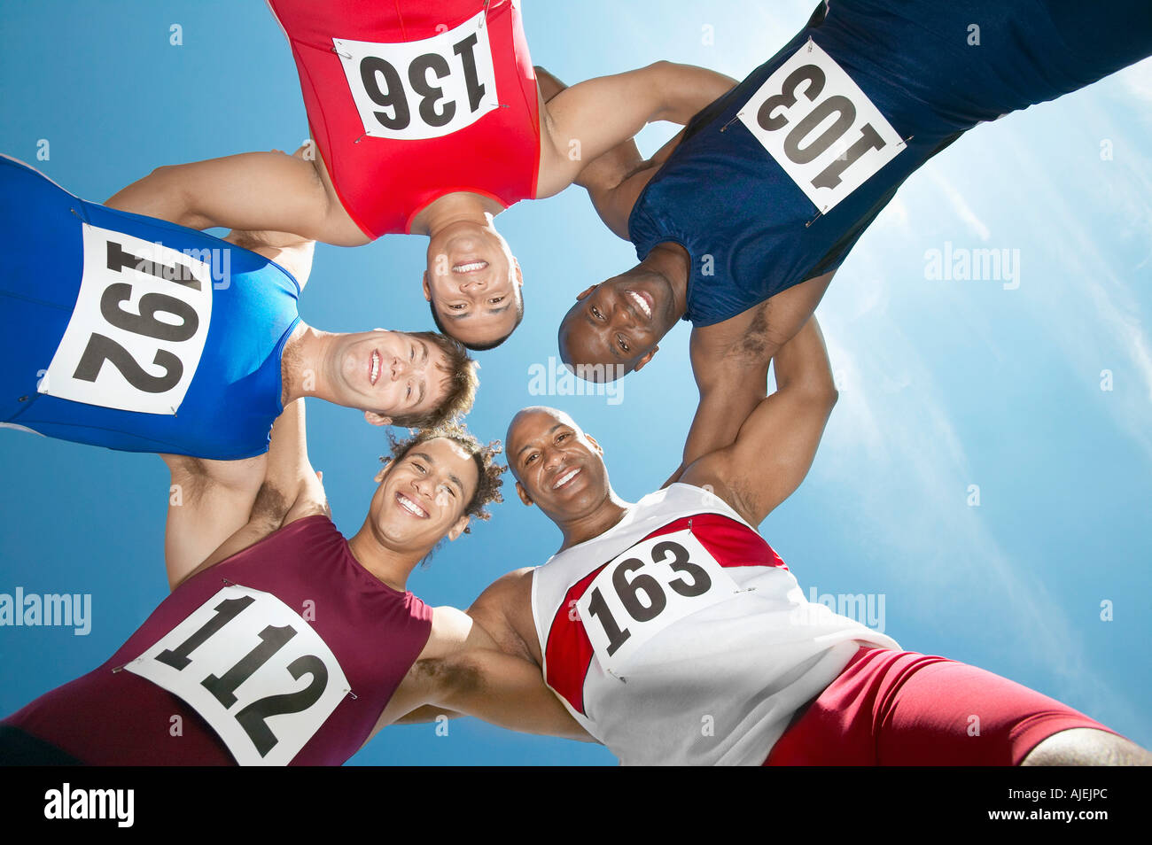 Track and field athletics smiling in a circle, view from below Stock