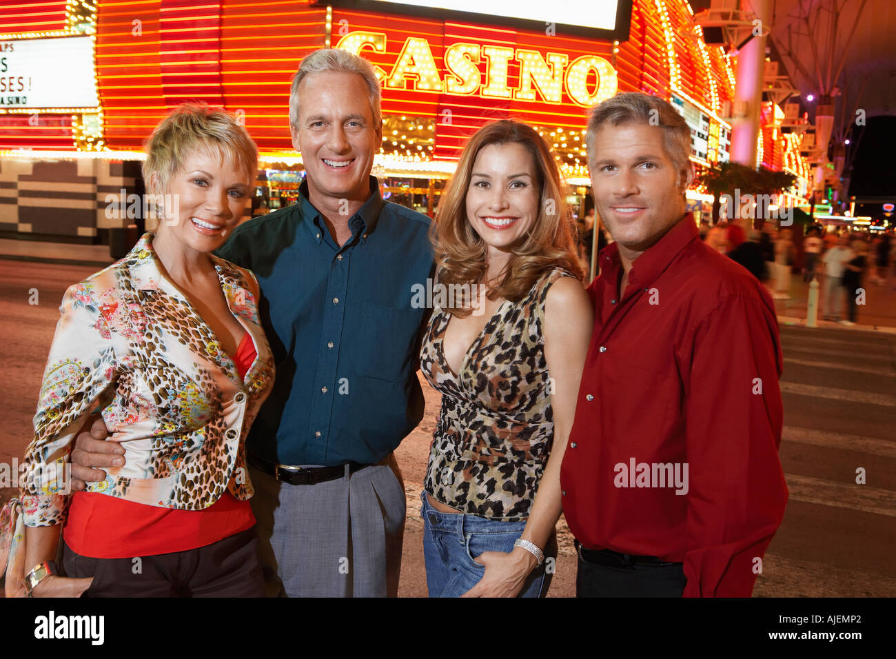 Two couples standing in front of illuminated casino, portrait Stock Photo