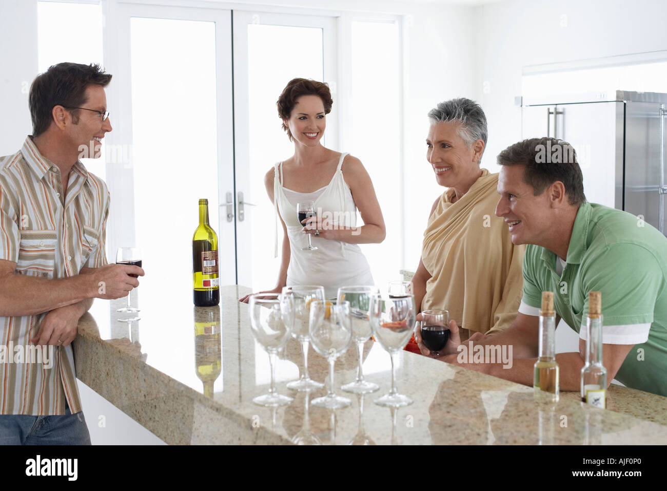 Two couples drinking wine in kitchen Stock Photo