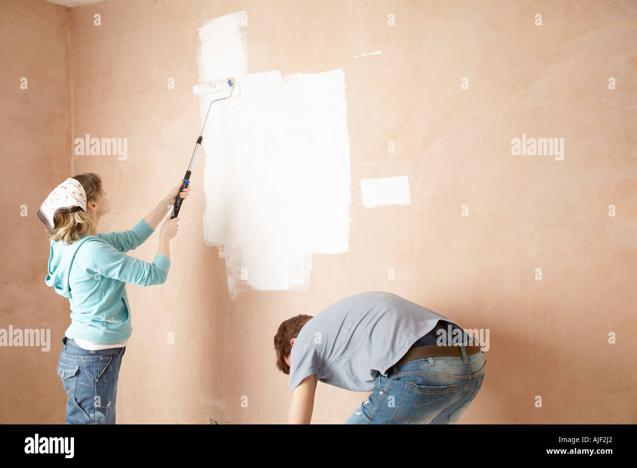 Couple using paint rollers on interior room Stock Photo