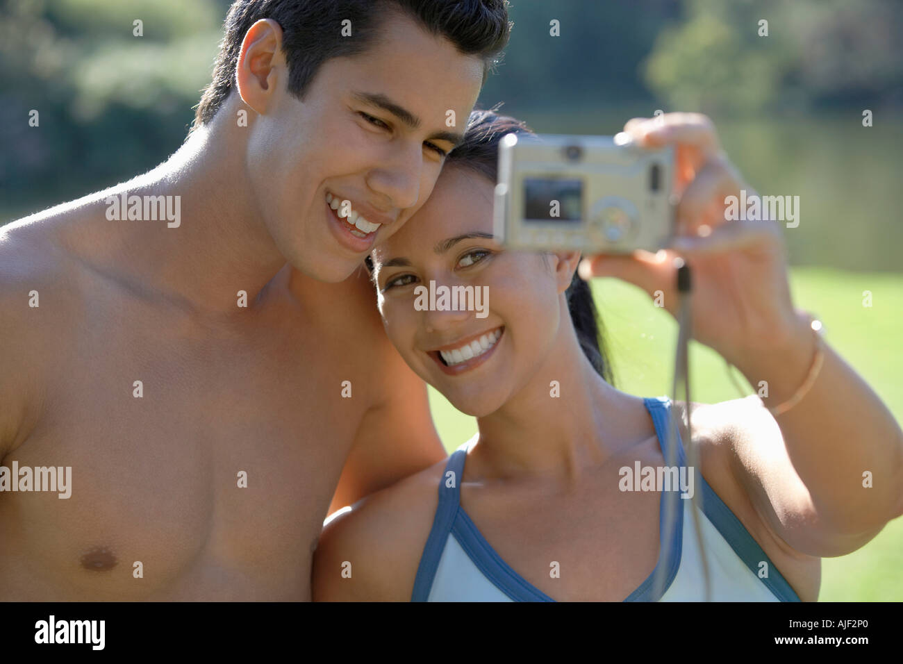 Couple photographing themselves, standing in park Stock Photo