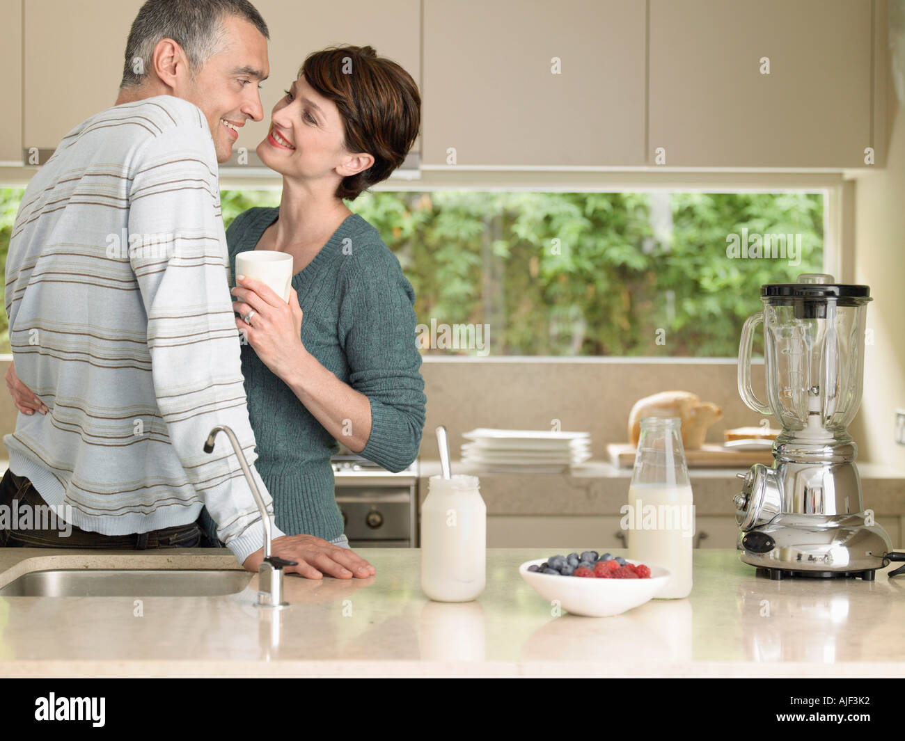 Smiling couple flirting in kitchen Stock Photo