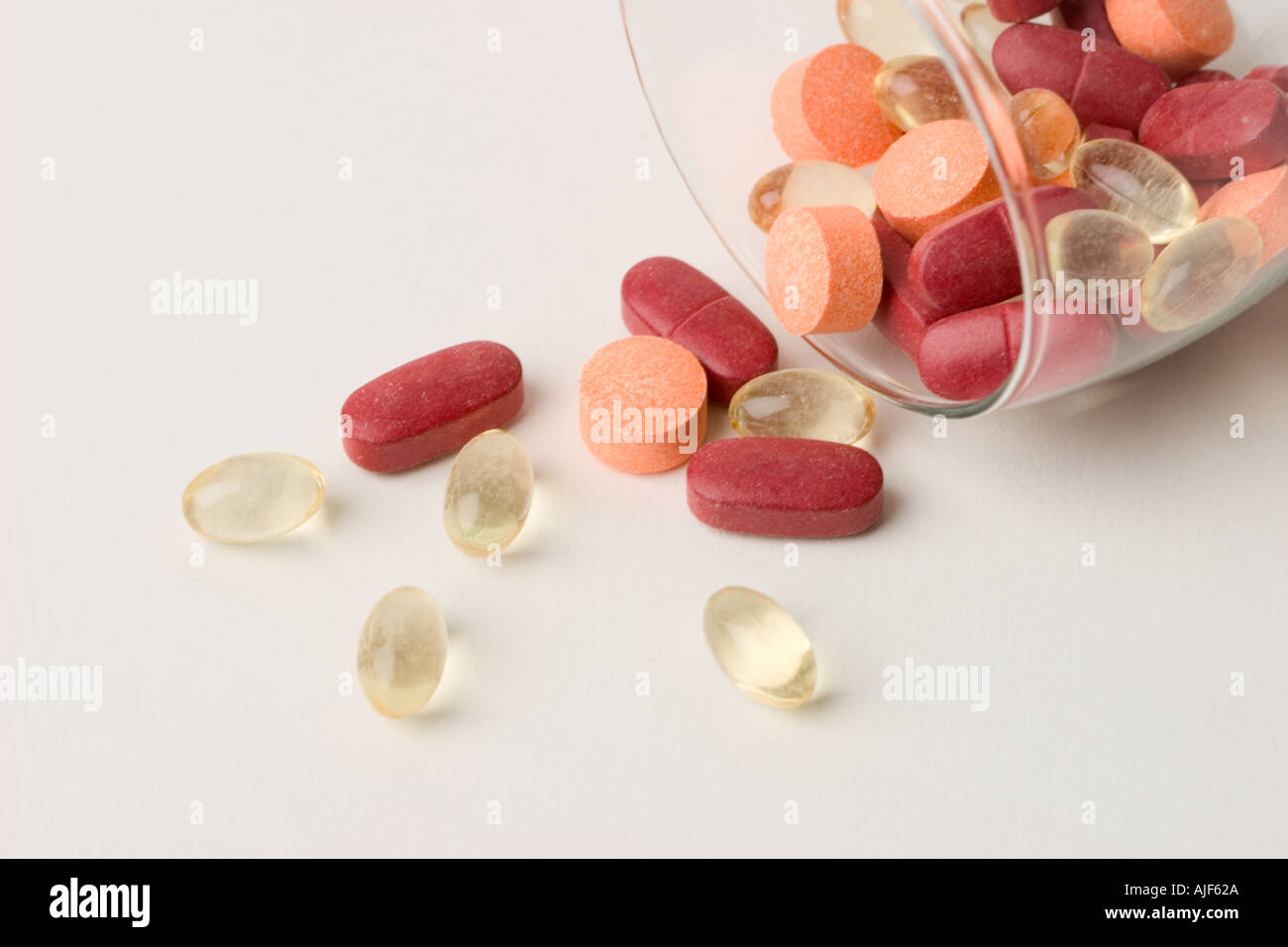 Assorted vitamin pills spilling out of wine glass Stock Photo