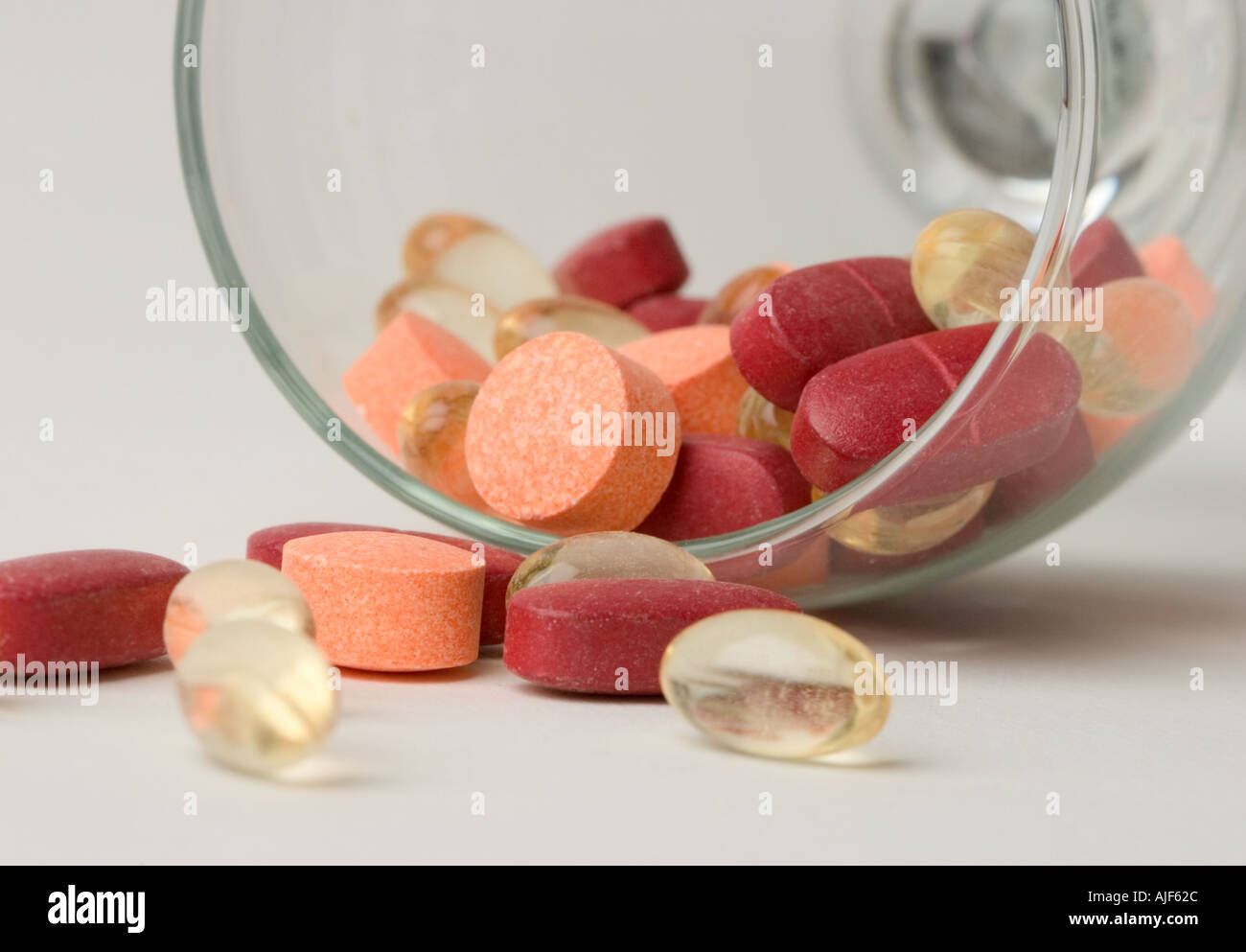 Assorted vitamin pills spilling out of wine glass Stock Photo