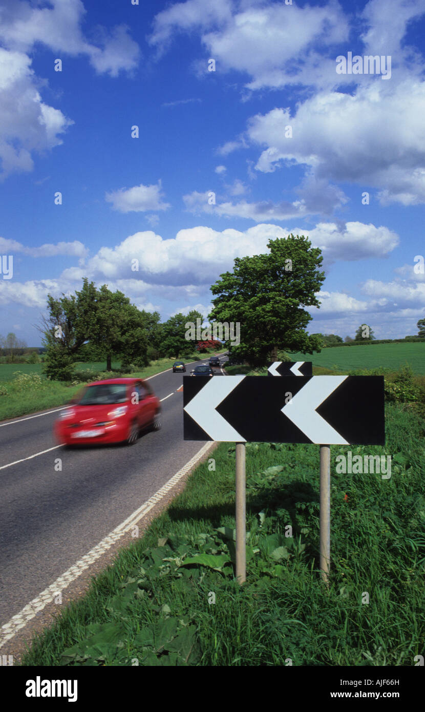 traffic passing black and white chevron warning signs of sharp bend on country road leeds yorkshire uk Stock Photo