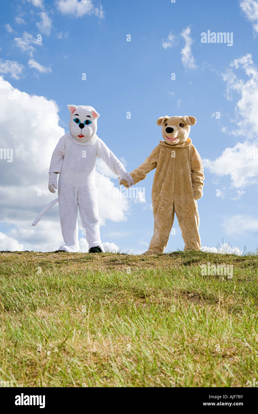 People in cat and dog costumes holding hands Stock Photo