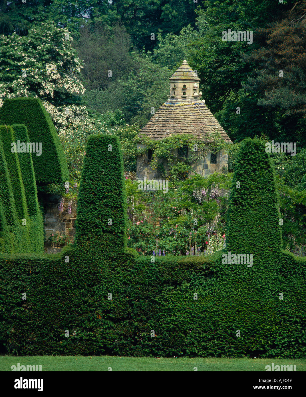 The Gazebo with doves in the garden at Nymans seen through clipped yews Sussex Stock Photo