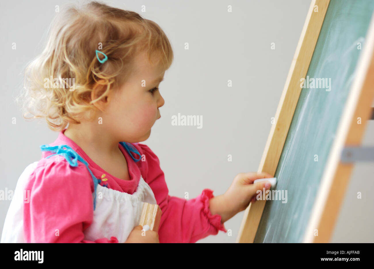 Two year old girl drawing on chalk board Stock Photo