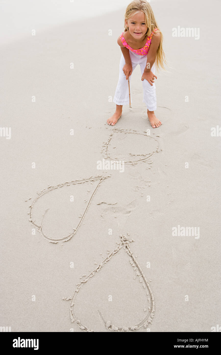 Girl drawing hearts on the sand Stock Photo