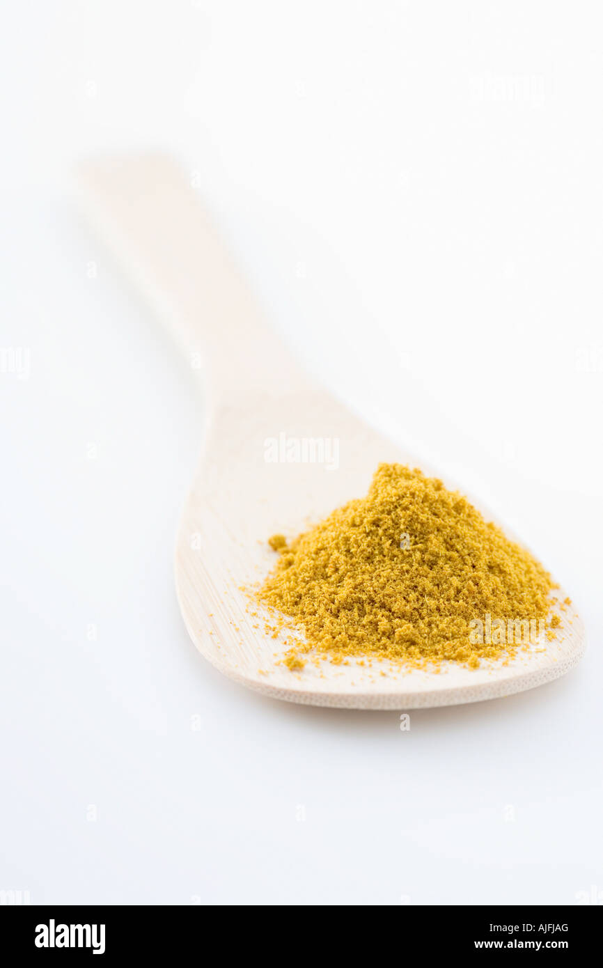 Curry powder and a wooden spoon Stock Photo