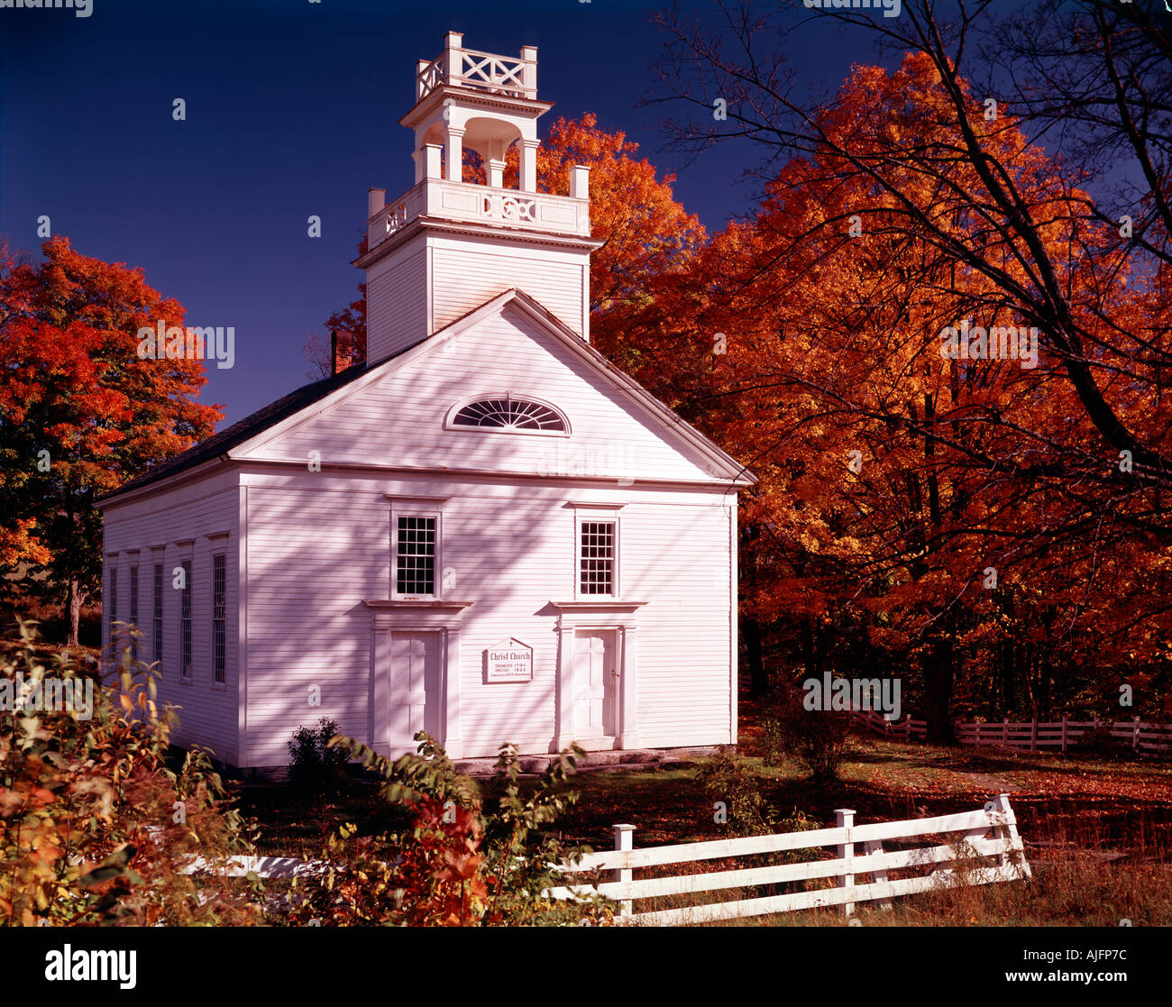 Bethel church in Vermont surrounded by flaming red maple trees in Autumnal glory Stock Photo