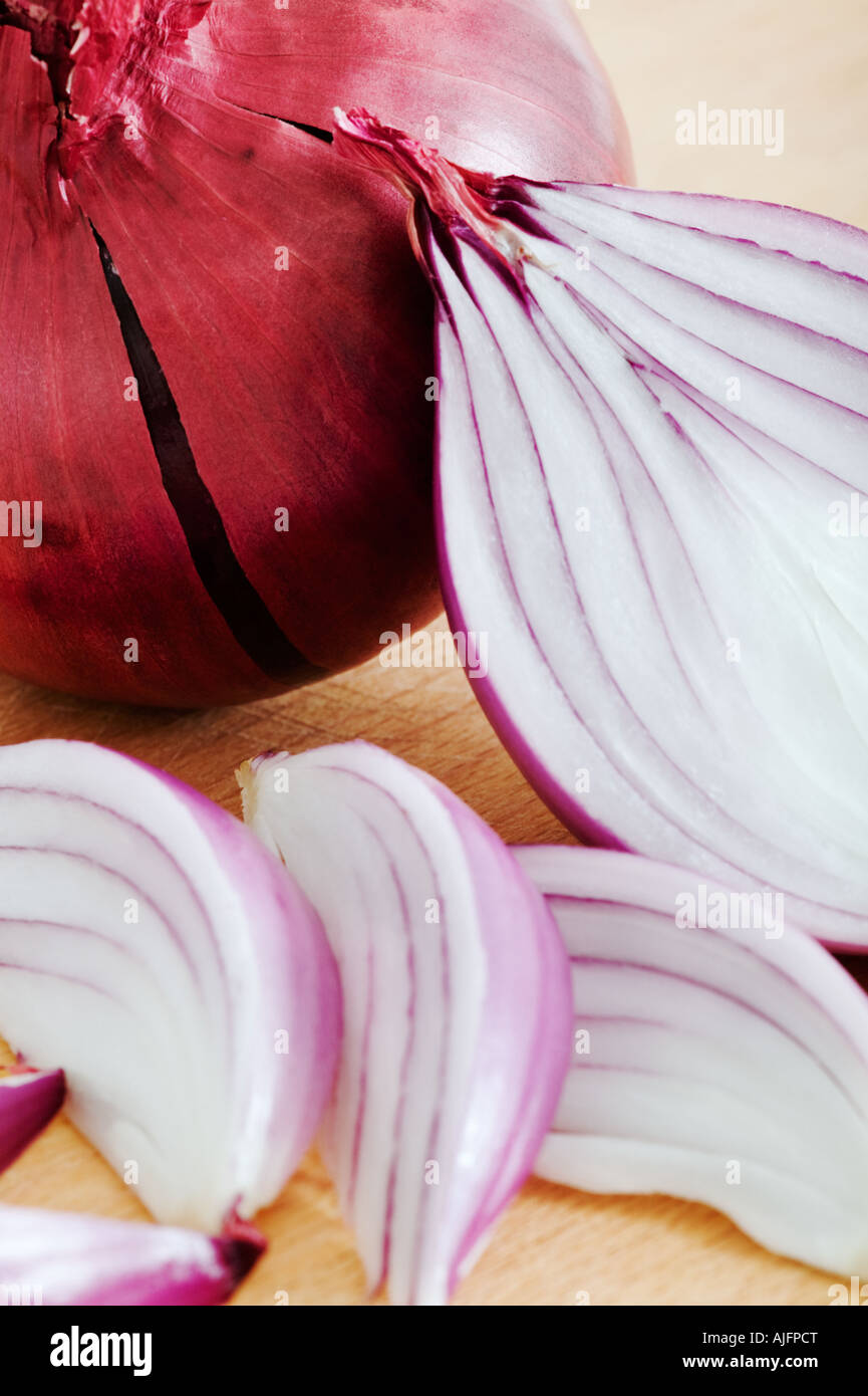 Red onions on wooden cutting board Studio shot against white background Stock Photo