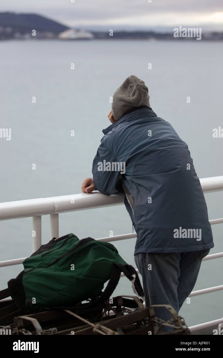 A passenger on a ship from the Alaska Marine Highway Ferry System looks at Haines in the distance Stock Photo
