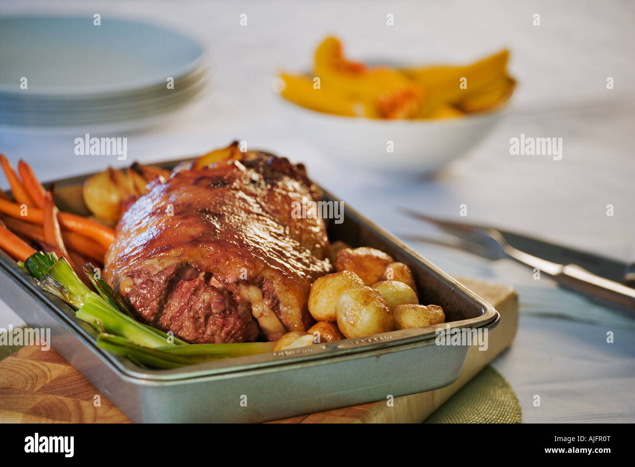 Roast lamb and vegetables In baking tray on a wooden board Stock Photo