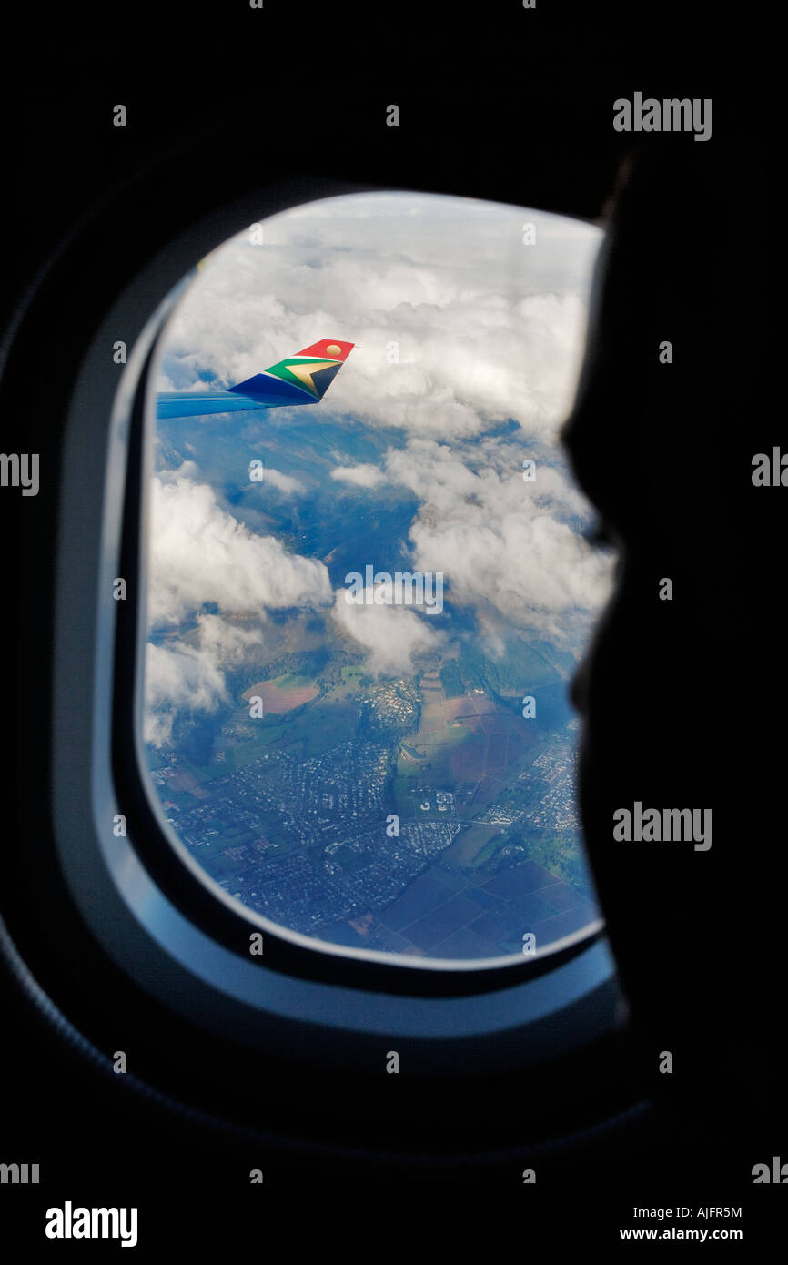 View of a plane wing through the window of the plane Tourist enjoying landscape below Model Released Stock Photo