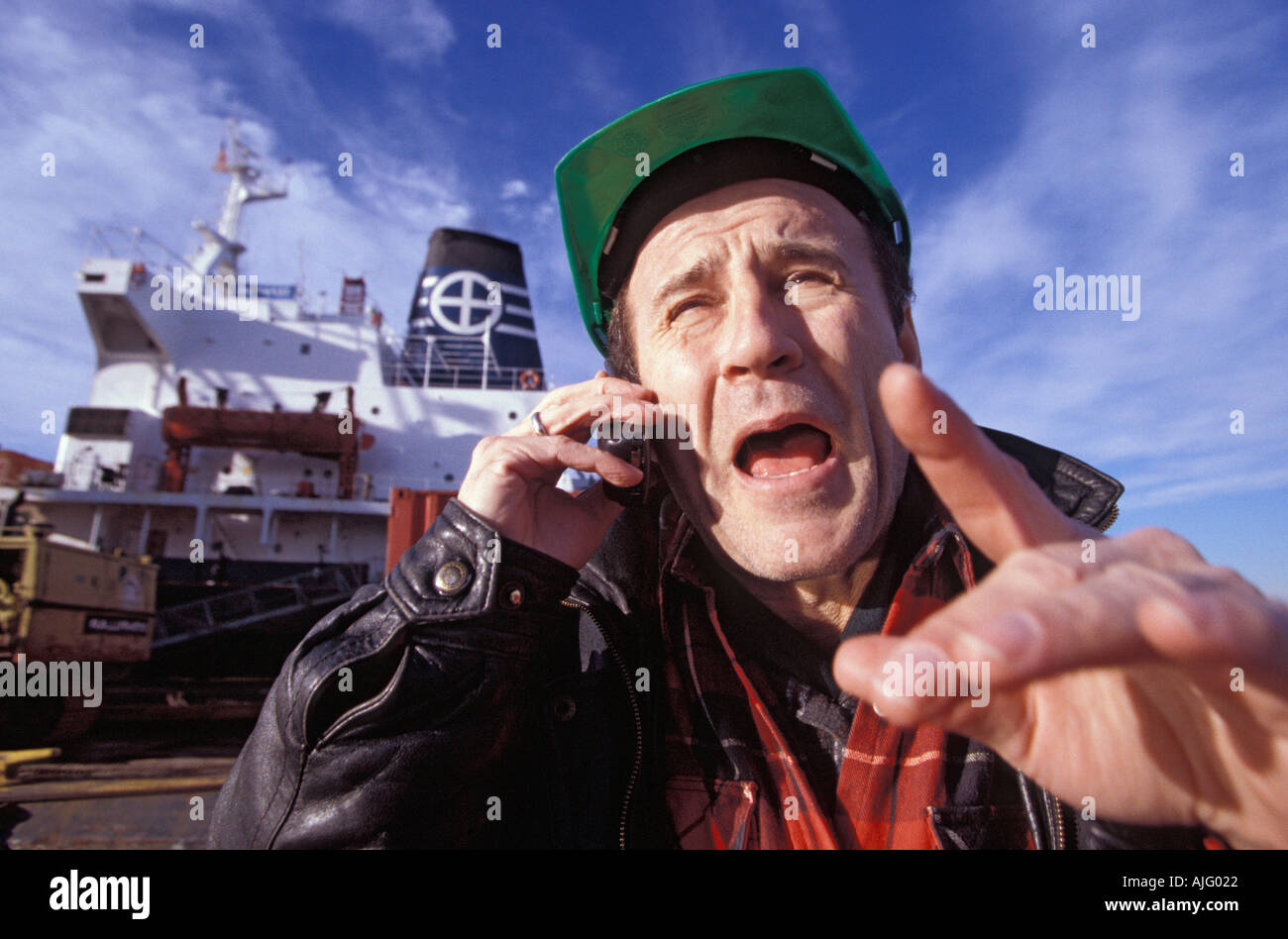 Caucasian longshoreman talking on cell phone Stock Photo