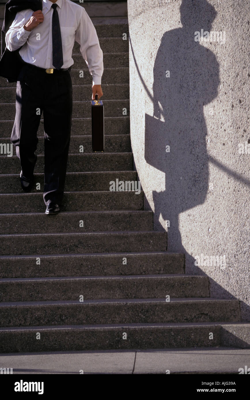 Caucasian businessman walking down stairs with shadow Stock Photo