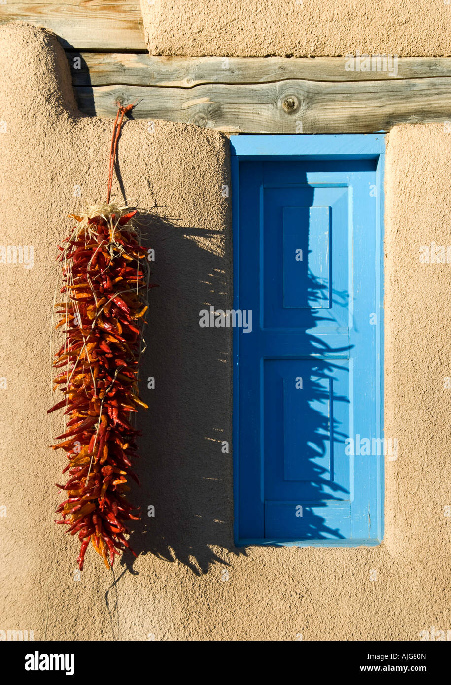Chiles adorn an adobe window in Taos, New Mexico Stock Photo