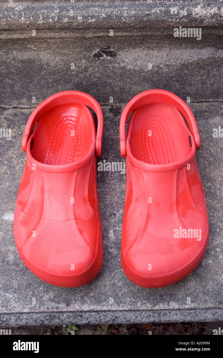 Pair of red adult croc sandals on step outside door Stock Photo