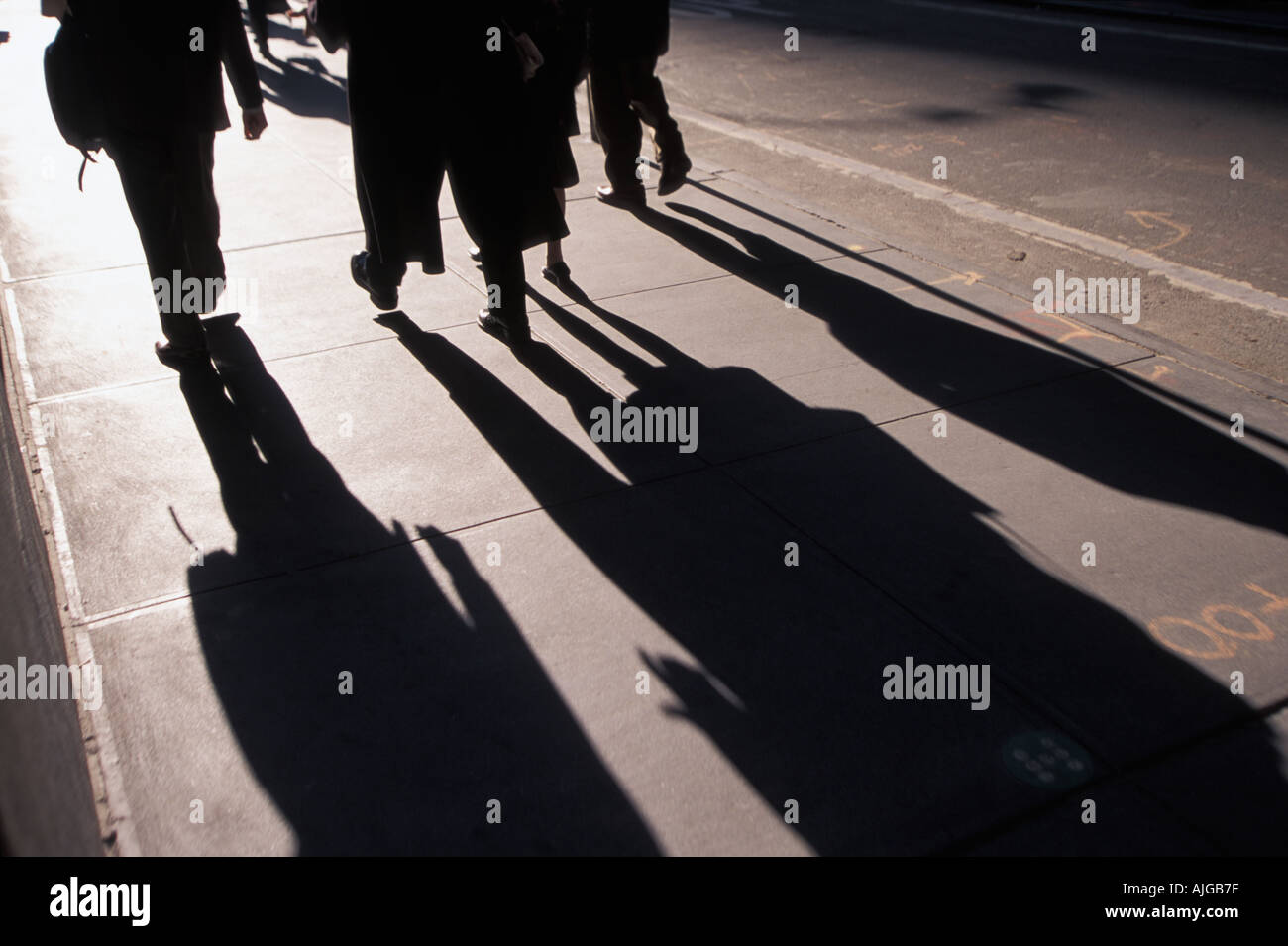 Shadows of anonymous executives walking along Wall Street Stock Photo