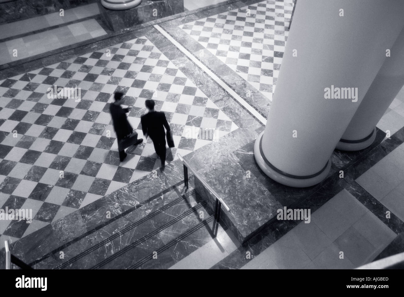 Two businessmen walking and talking in lobby Stock Photo - Alamy