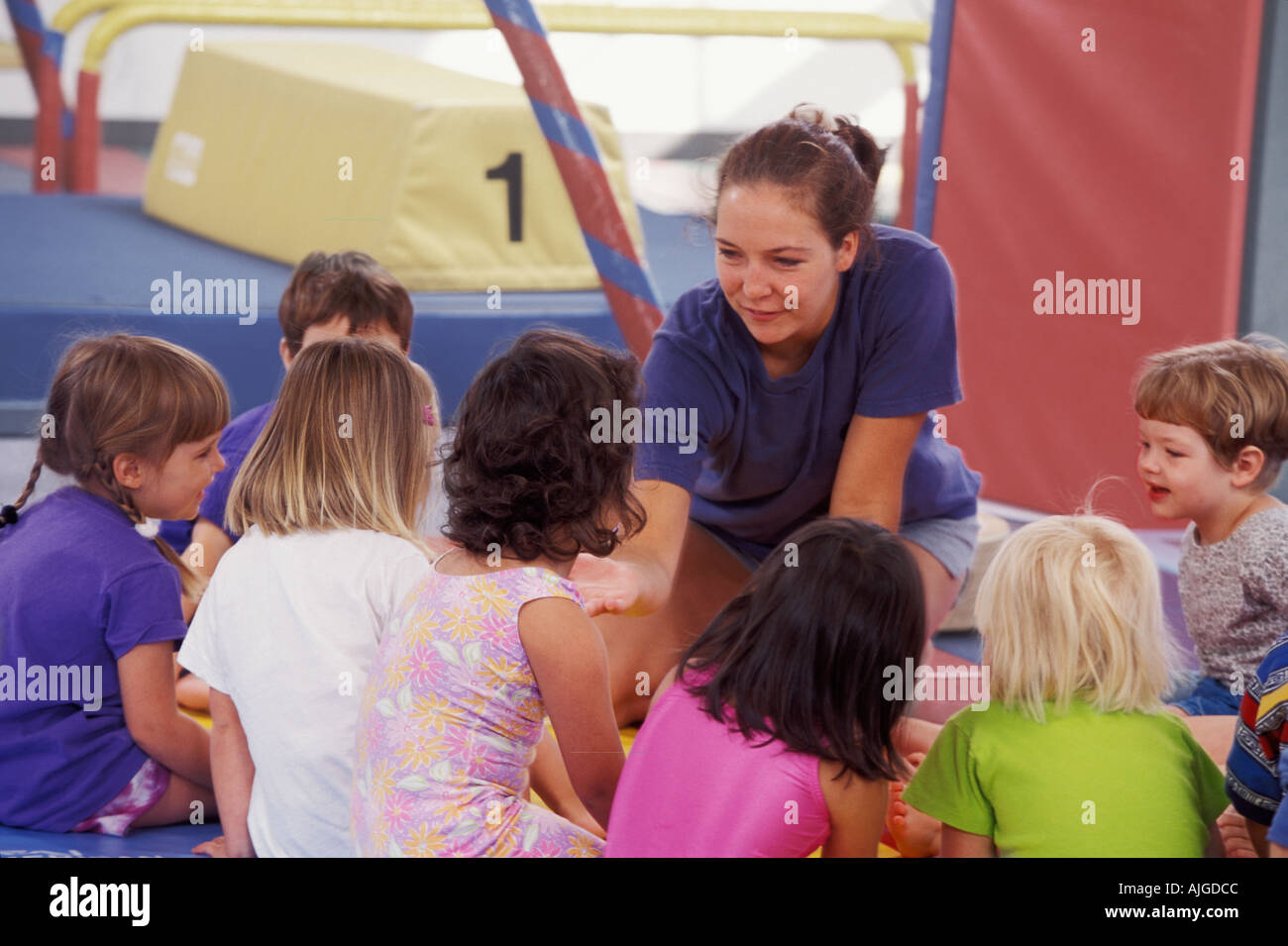 Caucasian teacher talking to students in preschool gym class Stock Photo